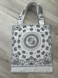 White tote bag with black paisley pattern on a wooden surface