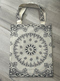 Cream tote bag with black paisley pattern on a gray surface