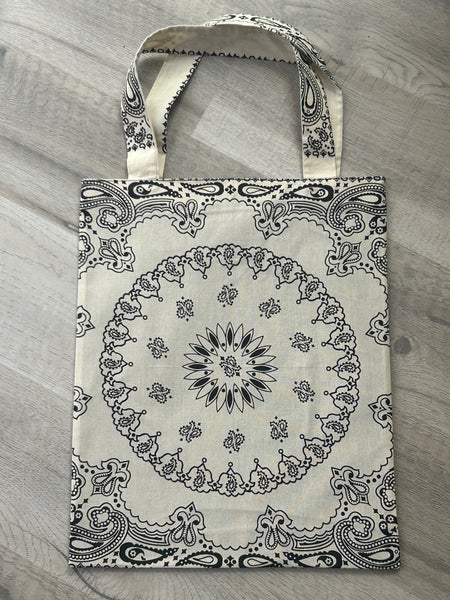 Cream tote bag with black paisley pattern on a gray surface
